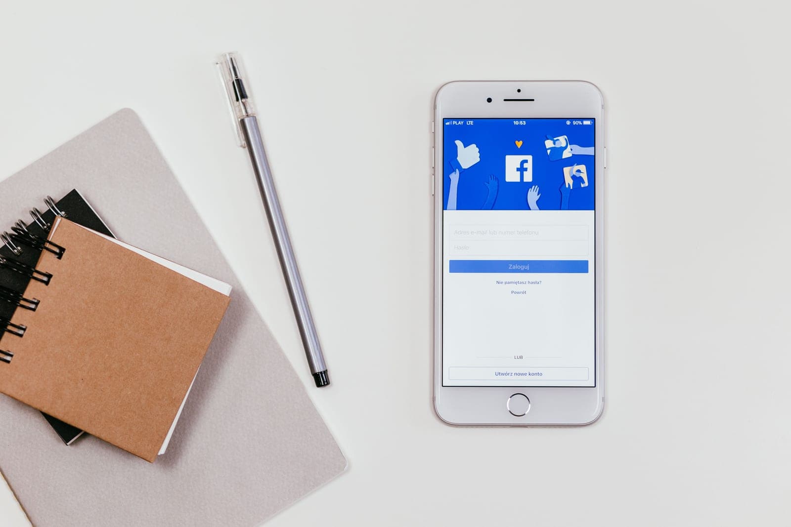 A phone showing the Facebook sign-in screen next to a notebook and pen